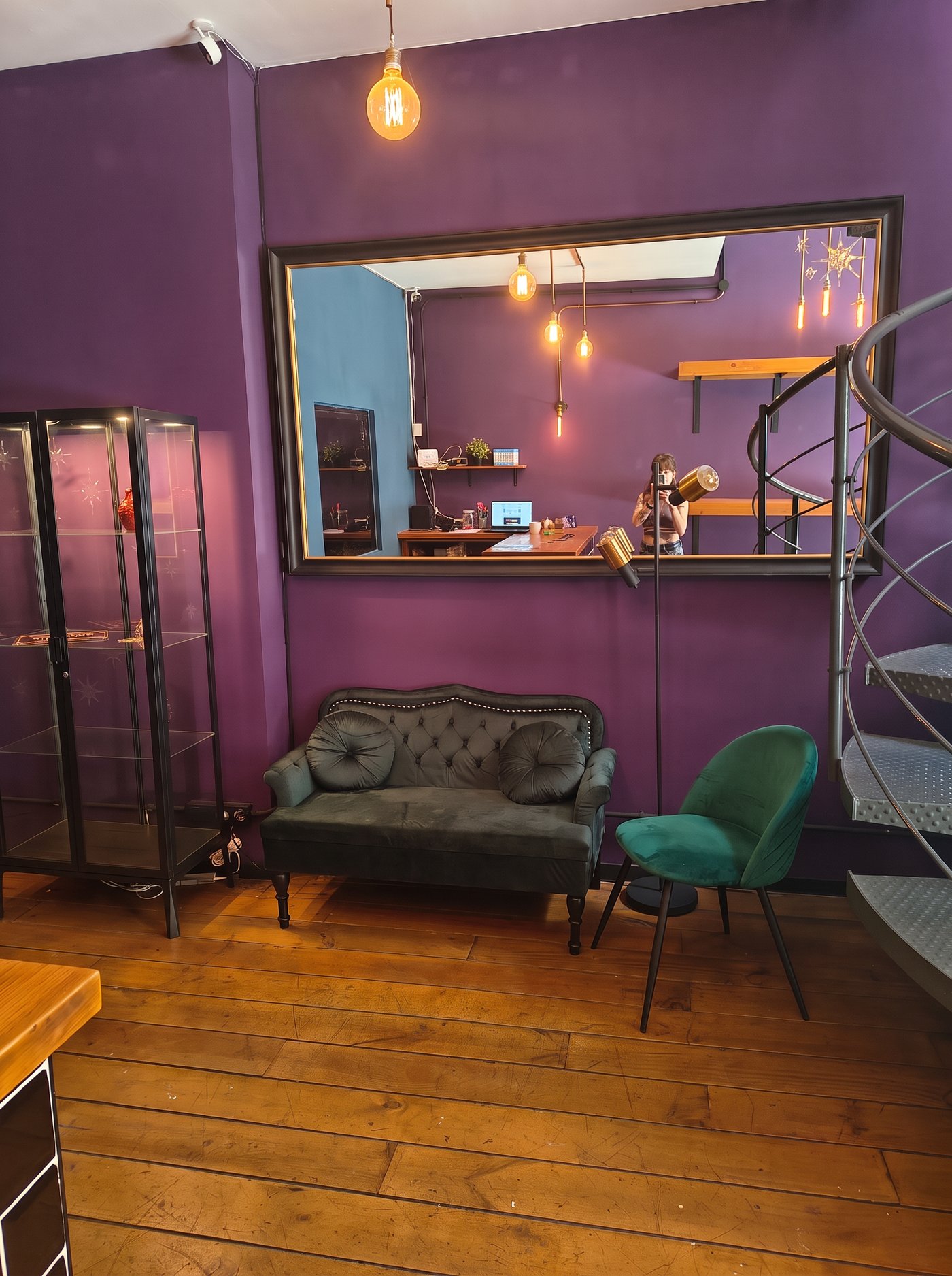 Sala de espera con sofá, butaca verde y escalera de caracol